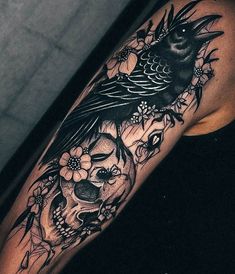 a woman's arm with a bird and skull tattoo on it