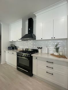 a kitchen with white cabinets and black stove top oven in the center of the room