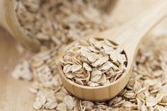 a wooden spoon filled with oats on top of a table