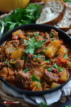 a bowl filled with meat and vegetables next to bread