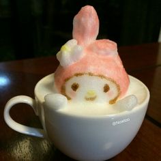 a hello kitty in a coffee cup on a table