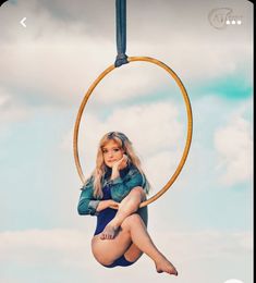 a woman sitting on top of a hoop in the air