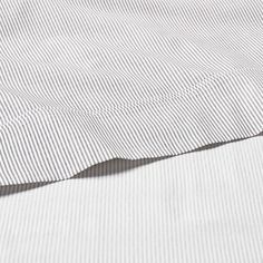 a close up view of a white and black striped bed sheet with an unmade pillow