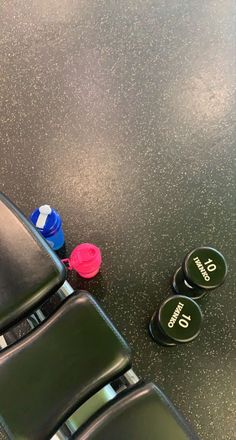 two plastic cups sitting on top of a black table next to green chairs and a red cup