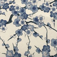 a blue and white flowered wallpaper with birds perched on the branch in front of it