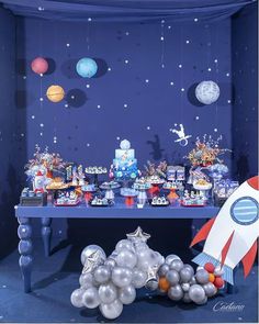 a space themed birthday party with balloons, cake and desserts on a table in front of a blue wall