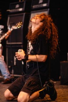 a man with long hair sitting on top of a stage