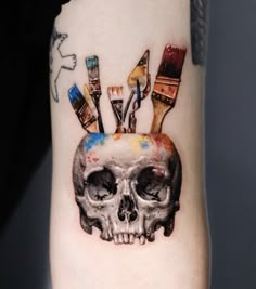 a skull with paintbrushes on it's head is shown in this artistic tattoo