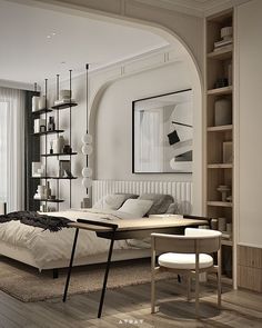 a large white bed sitting in a bedroom next to a wooden table and chair on top of a hard wood floor