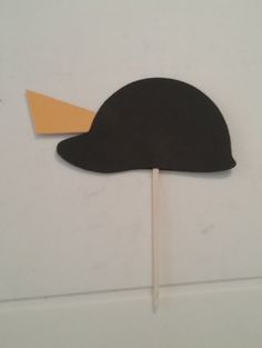 a black hat on top of a toothpick with an orange stick sticking out of it