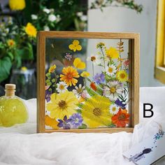 a wooden frame with flowers painted on it next to a bottle and flower vases