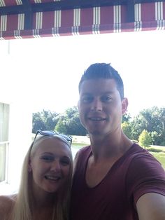 a man standing next to a woman in front of a red and white awning