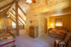 a bedroom with wooden walls and ceiling, two beds in the room and a rocking chair