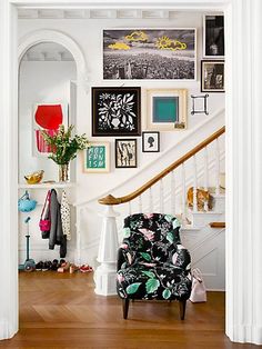 a living room filled with furniture and pictures on the wall next to a stair case