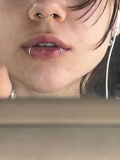 a close up of a person with ear piercings on her nose and headphones in their ears