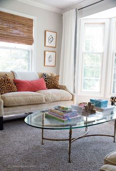 a living room with two couches and a glass table in front of the window