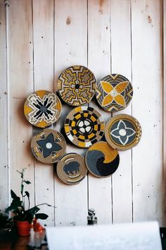 a bunch of plates that are on a wooden wall next to a potted plant