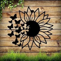 a metal sunflower and butterflies on a wooden wall with grass in the foreground