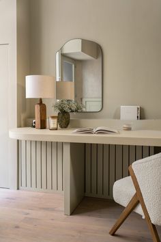 a desk with a mirror, lamp and vase on it