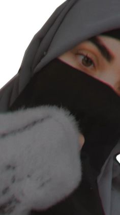 a woman wearing a black and grey hijab covering her face with a scarf