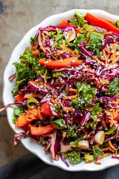 a salad with carrots, broccoli and red cabbage in a white bowl