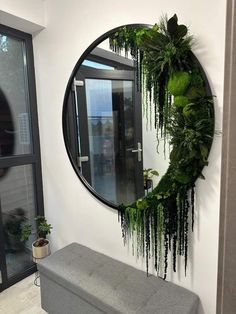 a round mirror hanging on the side of a wall next to a bench and potted plant