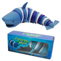 a blue and white toy fish in a box with its mouth open next to it's packaging