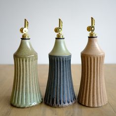 three ceramic vases sitting on top of a wooden table