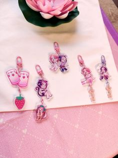 there are many charms on the table next to a pink flower and a white napkin