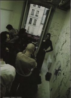 a group of people standing in front of a wall with writing on it and one person leaning against the wall