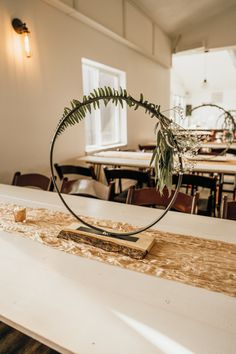 a wooden table topped with a metal ring and a fern plant on top of it