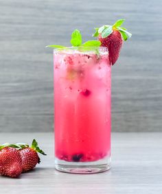 a pink drink with strawberries on the side