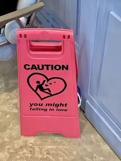 a pink caution sign sitting on the ground next to a blue door with a heart