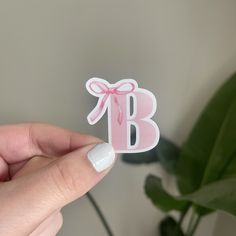 a person holding up a sticker with the letter b on it's side