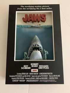 a movie poster for jaws with a shark coming out of the water in front of it