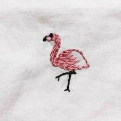 a pink flamingo embroidered on a white shirt