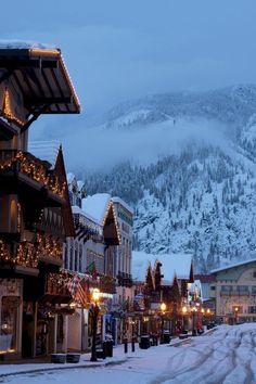 the town is covered in snow and lit up with christmas lights on it's buildings