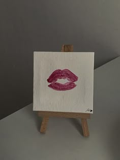 a small easel with a red lipstick painted on the front and side of it