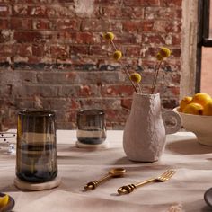 a table topped with plates and bowls filled with fruit next to a brick wall covered in windows