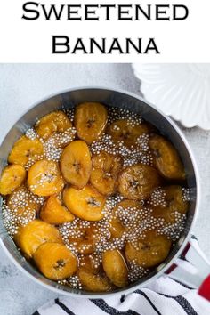 a pan filled with bananas sitting on top of a white table next to a plate