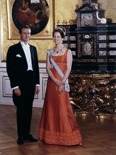 a man and woman in formal wear standing next to each other on a wooden floor