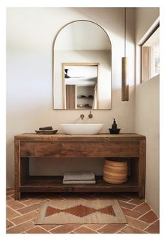 a bathroom sink sitting under a mirror next to a wooden counter top with a bowl on it