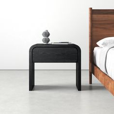 a bed with a wooden headboard next to a night stand on the side of it