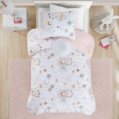 a white and pink bed with stars, moon and clouds on the comforter set