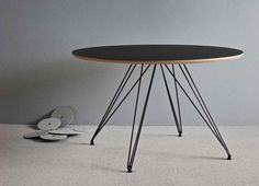 a table with black top and metal legs on carpeted floor next to white wall