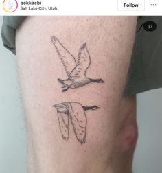 a man with a tattoo on his leg that has two birds flying in the sky