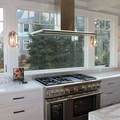 a stove top oven sitting inside of a kitchen next to a window with lots of windows