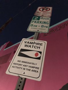 two street signs on a pole in front of a pink building