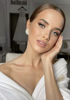 a woman in a white dress posing for the camera with her hand on her chin