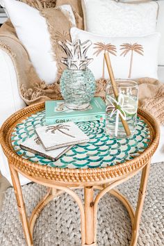 a wicker coffee table topped with books and a pineapple on top of it